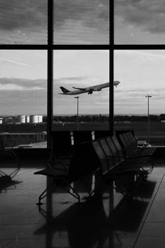 black and white photograph of an airport terminal with planes in the air, looking out windows