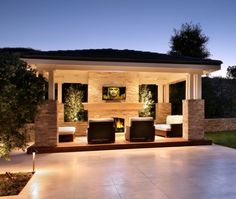 an outdoor living area with couches and fire place at night in front of a house