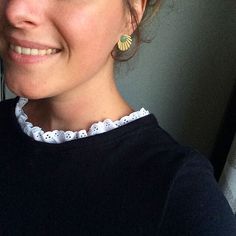 a woman wearing a black shirt and earrings smiling at the camera with her hand on her hip