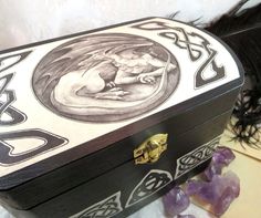 a black and white box sitting on top of a table next to some rocks with purple crystals around it