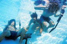 three people are swimming in the water with their feet up and holding onto skis