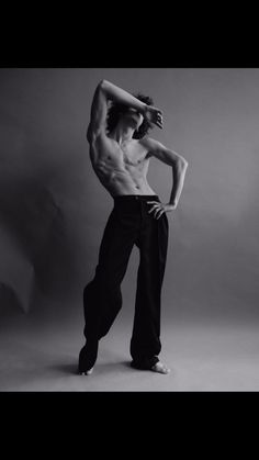 a shirtless man poses for a black and white photo with his hands on his head