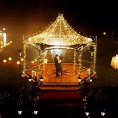 two people standing under a lit up gazebo