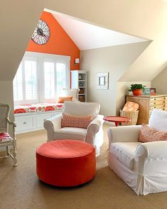 a living room filled with furniture and a clock mounted on the wall above it's windows