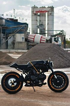 a black motorcycle parked on top of a dirt field next to a pile of dirt