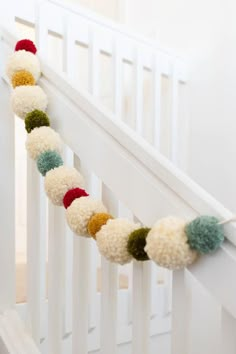 a white crib rail with multi colored pom - poms on it