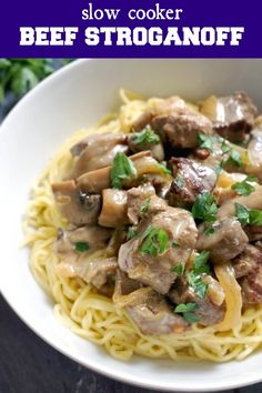 beef stroganoni with mushrooms and parsley in a white bowl on top of noodles