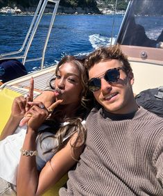 a man and woman sitting on the back of a boat pointing at something in front of them