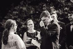 black and white photograph of a man holding his hand to his ear while looking at the bride