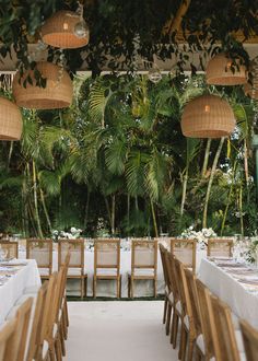 tables and chairs are set up for an outdoor wedding reception with hanging bamboo lanterns above them