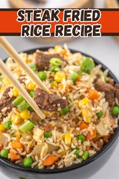 steak fried rice with vegetables and chopsticks in a black bowl on a white table