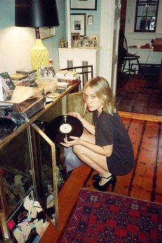 a woman kneeling on the floor with a record