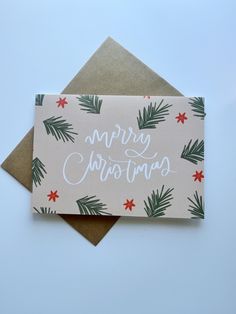 a christmas card with the words merry christmas written in white ink on top of an envelope