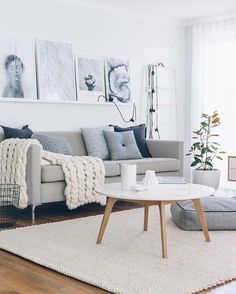 a living room with white walls and wooden flooring, gray couches, rugs and pictures on the wall