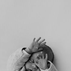 a black and white photo of a baby with his hands in the air above his head