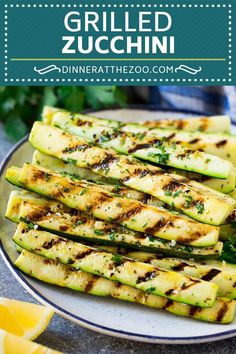 grilled zucchini on a plate with lemons and parsley in the background