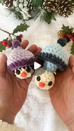 two small crocheted snowmen are in the palm of someone's hand