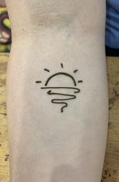 a small sun tattoo on the arm