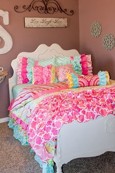 a bed with pink and blue comforter in a bedroom next to a wall clock