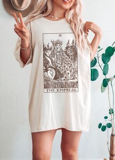 The Empress Tarot Card Shirt Please reach out if your desired color, size or garment style is not available! Be sure to check the size chart within the listing. Most of the models are wearing oversized apparel. Size up from your usual size to achieve this look! TEE INFO/CARE: * Solid colors are 100% cotton except Ash - 99% cotton and 1% polyester, heather colors are 52% cotton and 48% polyester * Pre-Shrunk * Unisex, Loose fit * Wash inside out in COLD water * Lay flat to dry or machine dry on LOWEST setting * Iron on low * Do NOT dry clean Printed with eco-friendly DTG (Direct to Garment Printing) technique. Inks are water based, bio-degradable and non-toxic. Artwork is digitally transferred directly onto the fabric, giving it a worn-in look. The printed material will be less stiff than t Tarot Tshirt, The Empress Tarot, Witchy Clothes, Tarot Shirt, Tarot Card Shirt, Empress Tarot Card, Empress Tarot, Vintage Tarot, Indie Clothing