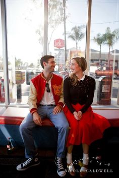 a man and woman sitting next to each other on a bench in front of a window