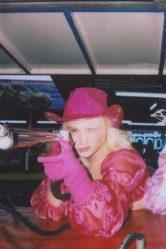 a woman wearing pink gloves and a red hat sitting at a table in front of a camera