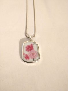 Free 18" Silver plated  "Snake" Chain no returns or Exchanges  Free 18" Silver plated  "Snake" Broken China Jewelry Broken China Pendant Broken China Jewelry, Pendant. Sterling Sliver, OOAK,red & Pink Flowers. Every piece of  broken china is unique and carefully handcrafted . Each piece is stamped with the artists name  All pieces are bezelled in fine silver. Bail and backing are sterling. We  use broken china plates and dishes. We are happy to make a custom item using your heirloom pieces. Hand Painted White Sterling Silver Jewelry, Artistic White Sterling Silver Necklace, Hand-painted White Sterling Silver Jewelry, Artistic Sterling Silver White Necklace, Handmade White Rectangular Pendant Jewelry, White Hand Painted Round Necklaces, White Hand Painted Round Necklace, White Hand Painted Round Pendant Necklaces, Hand Painted White Round Pendant Necklaces