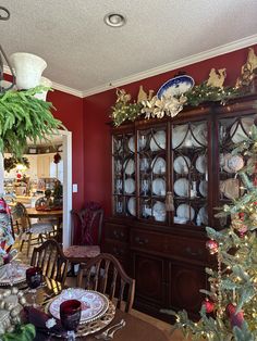 the dining room table is set for christmas with plates and silverware on it's china cabinet