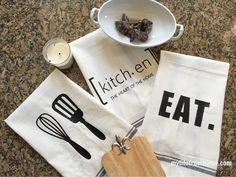 kitchen towels with utensils on them sitting next to a bowl of chocolates