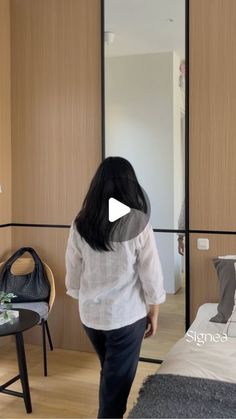 a woman is walking in front of a bed and mirror with the words singeng on it