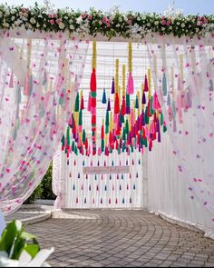 an outdoor ceremony with colorful streamers hanging from the ceiling and flowers on the wall