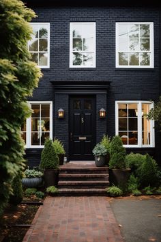 a black house with white windows and steps leading to the front door