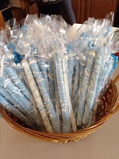 a basket filled with lots of blue and white paper wrapped in cellophane on top of a table