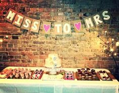 a table topped with lots of cupcakes next to a brick wall