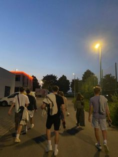 group of people walking down the street at night with backpacks on and one person wearing shorts