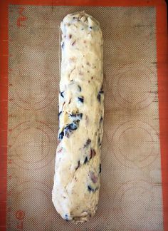 a loaf of bread sitting on top of a piece of paper covered in blueberries