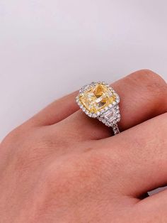 a woman's hand holding a yellow and white diamond ring