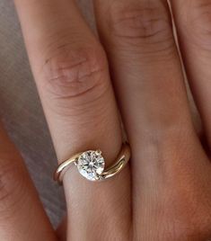 a woman's hand with a gold ring and a white diamond on the finger