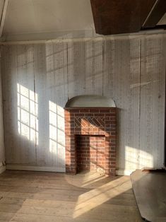 an empty room with a brick fireplace in the middle and sunlight coming through the windows