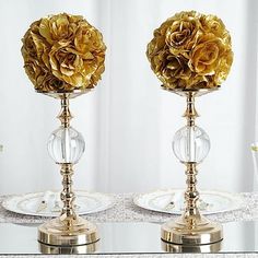 two vases with gold flowers on them are sitting on a glass table next to each other