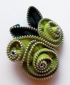 a green brooch with silver beads on it