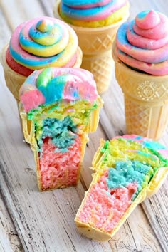 three ice cream cones with different colored frosting on top of each cone and one is cut in half