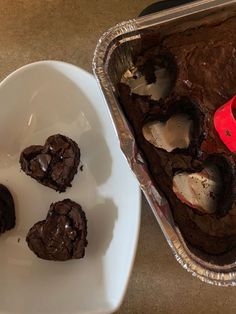 some chocolate desserts are on a white plate next to a baking pan with one cut in half