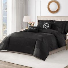 a bed with black comforter and pillows in a white room next to a window