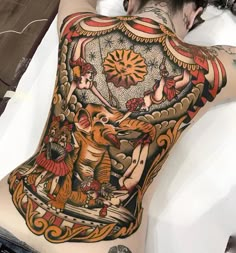 a man with tattoos on his back laying in bed