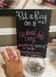 a woman's hand with pink and white nails next to a sign that says put a ring on it