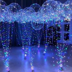 an array of balloons floating in the air with blue lights and streamers all around them