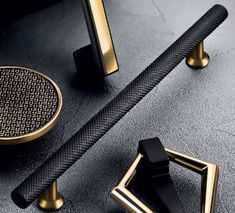 two black and gold door handles on a gray surface with an intricate design in the middle