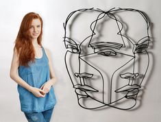 a woman standing next to a wire sculpture