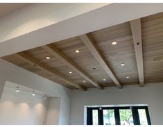 an empty room with wooden ceiling and windows